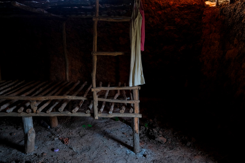 CAPTION in Shakahola, Kenya on 23 January, 2024. (Photo by Kabir Dhanji). A night dress hangs on a sturdy bed in a hovel in Shakahola. Lascivious artifacts litter the ruins of the camp, described by a neighbour as ‘Sodom and Gomorrah’. Many children were born in these hovels and never registered, killed and buried in the bush, disappearing without trace. A monastery it wasn’t.